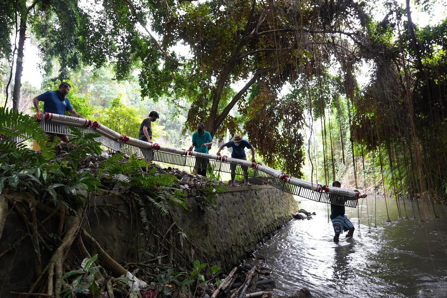 Sungai Watch river warriors install a river barrier that will float on the water and collect trash. 